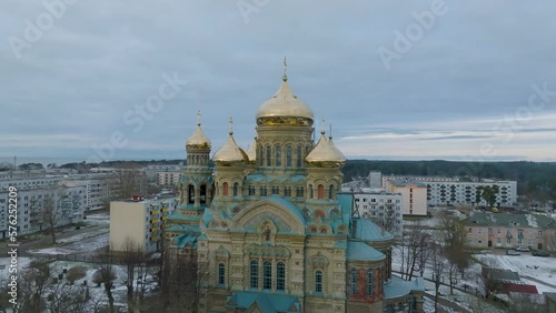 Aerial establishing view of orthodox (Russian) Karosta St Nicholas Naval Cathedral golden domes with crosses, cloudy winter evening, Liepaja (Latvia), orbiting drone shot moving right photo