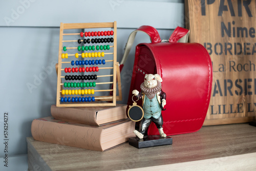 Modern interior study room with Workplace for school child. Desk in child bedroom. Red backpack, Books, abacus, figurine hare on wooden table. Written on the board Toulouse, Dijon, Bourges, Paris, Nim photo