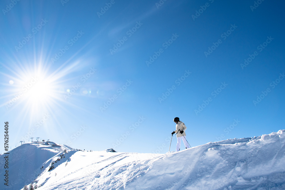 Skier on the mountain looking at the landscape with bright sun enjoying the snow and the ski resort. Doing sports outdoors. Lifestyle