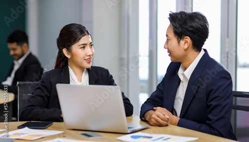 Millennial Asian professional successful male businessman manager mentor helping coaching advising new female businesswoman employee staff in formal business suit sitting working with laptop computer © Bangkok Click Studio