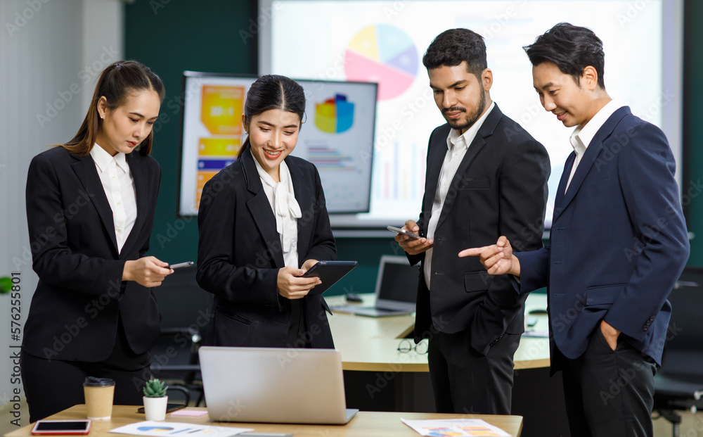 Millennial Asian Indian professional male businessmen female businesswomen employee staff colleagues in formal business suit standing discussing brainstorming working together with laptop computer Millennial Asian Indian professional male businessmen female businesswomen employee staff colleagues in formal business suit standing discussing brainstorming working together with laptop computer
