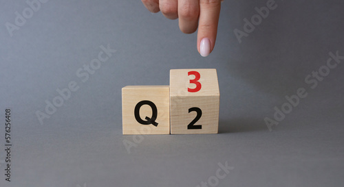 From 2nd Quarter to 3rd symbol. Businessman hand points at turned wooden cube with words 2nd Quarter and 3rd Quarter. Beautiful grey background. Business and Quarter concept. Copy space