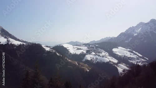 Aerial Flying Over Tree Line With Epic View Of Snow Capped Mountain Landscape Of The Italian Alps In The Background. Dolly Forward photo