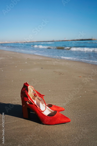 Red high heels with retro style abandoned in a seashore near the sea