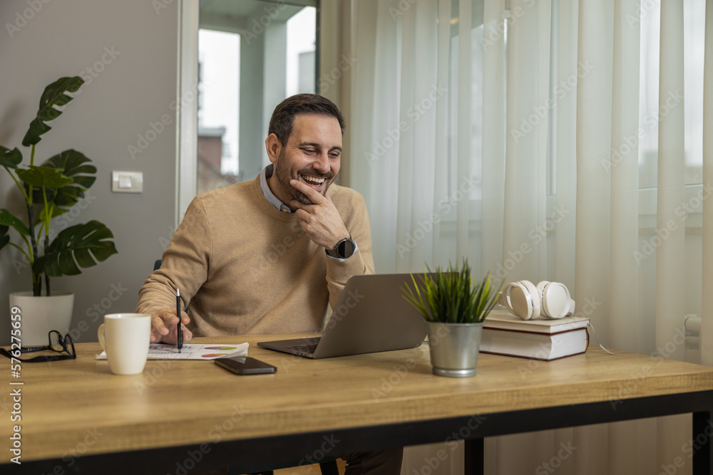Young man in casual clothing using laptop while working at home Young man in casual clothing using laptop while working at home