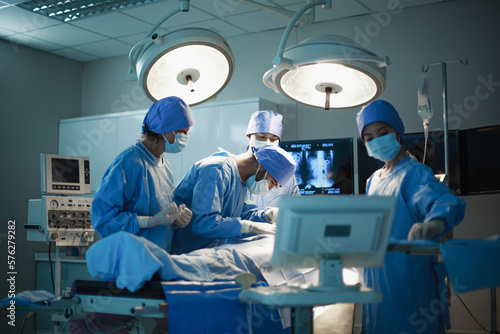 Doctor of or Surgeon, Medical team performing surgical operation in bright Modern operating room with art lighting and blue filter in hospital. Professional Medical Doctors Performing Surgery.