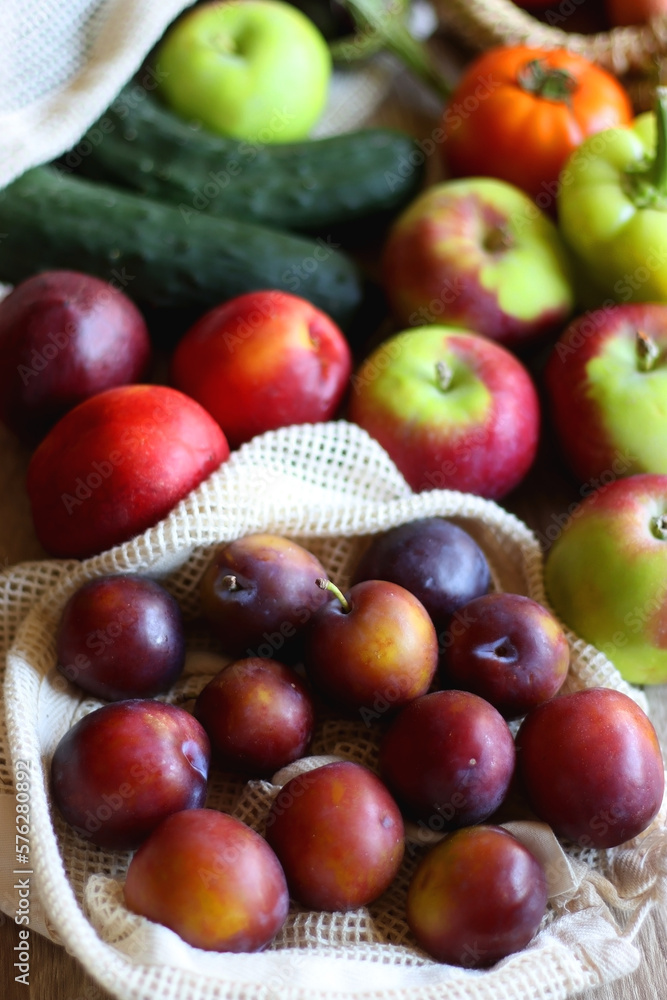 Straw bag and reusable fabric bags filled with various healthy fruit and vegetables. Wooden background, selective focus. Straw bag and reusable fabric bags filled with various healthy fruit and vegetables. Wooden background, selective focus.