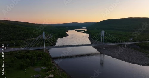 Aerial view around the Sami Bridge and Teno river, midnight sun in Utsjoki, Finland - circling, drone shot photo