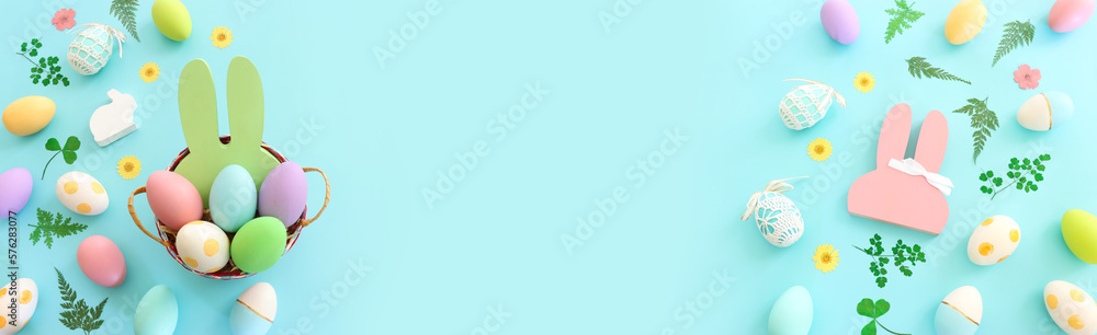 Cute bunny next to easter colorful eggs over blue pastel background Cute bunny next to easter colorful eggs over blue pastel background