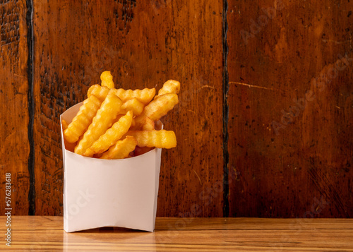 Valokuva crinkle cut fries on a wood background