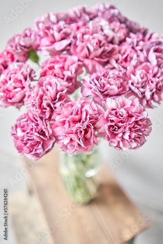 Beautiful pink carnation flowers in a vase on a table . Bouquet of light pink flower. Decoration of home. Wallpaper and background. fuchsia color