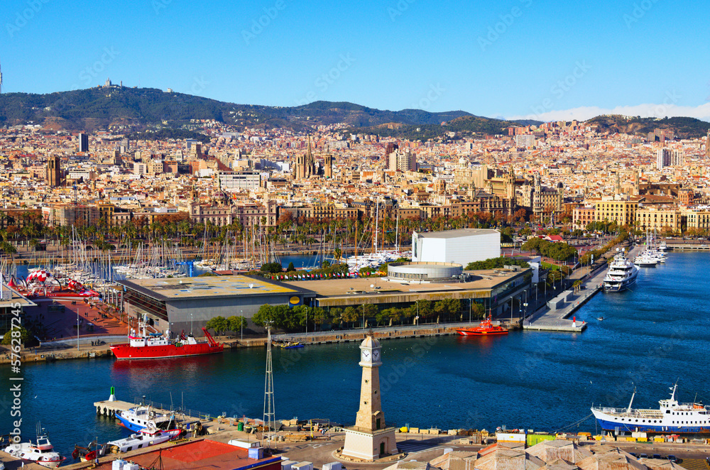 Picturesque aerial landscape view of Port Vell with moored yachts and ships in Barcelona. Downtown of Barcelona in the background. Travel and tourism concept. Cityscape at sunny day