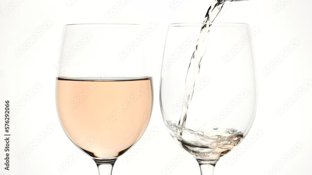 Pouring rose wine into glass from the bottle on the white background Pouring rose wine into glass from the bottle on the white background