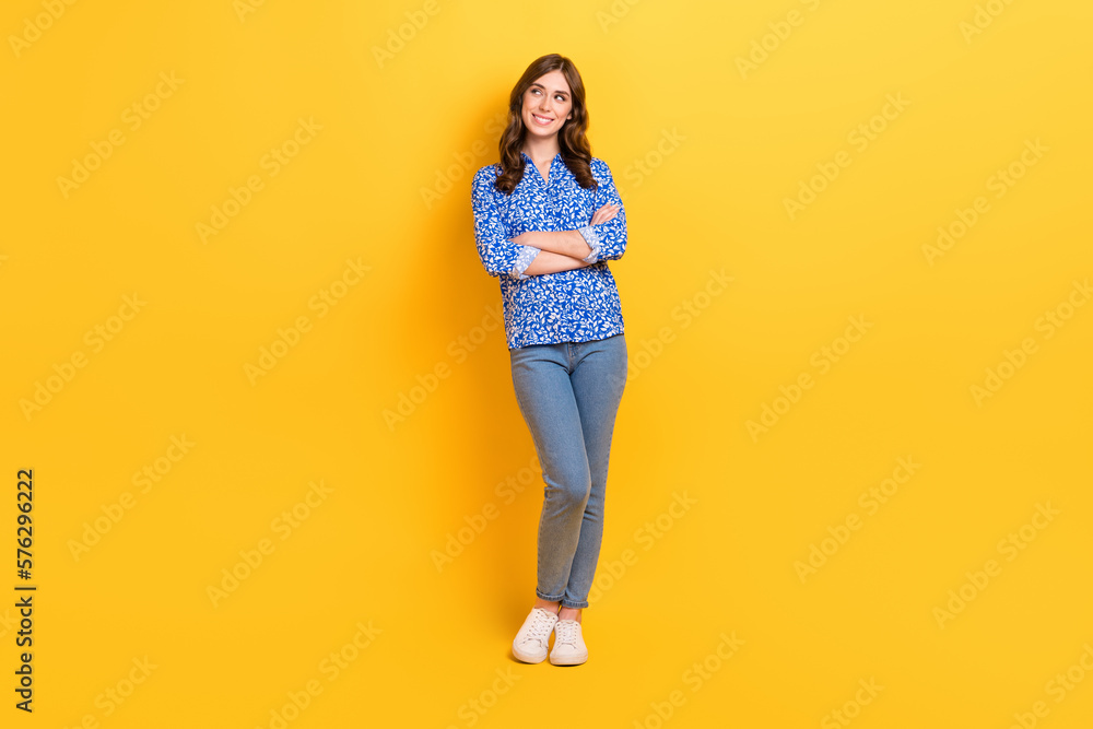 Full body photo of charming cheerful lady folded arms look empty space smart casual clothes isolated on yellow color background Full body photo of charming cheerful lady folded arms look empty space smart casual clothes isolated on yellow color background