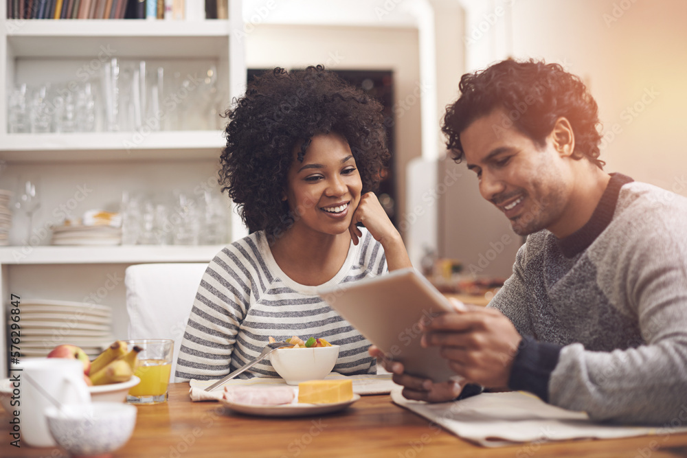 Starting the day together. Shot of a couple using a digital tablet while having breakfast at home. Starting the day together. Shot of a couple using a digital tablet while having breakfast at home.