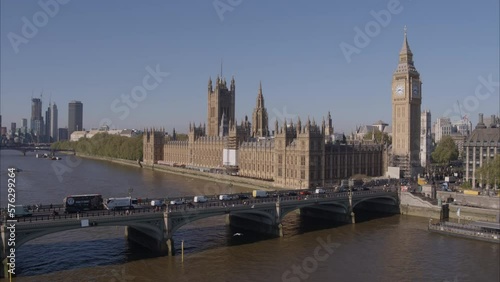 Aerial drone shot flying fast towards Westminster Bridge, Westminster Abbey and Big Ben over the River Thames with London Buses and traffic crossing Westminster Bridge on a bright clear sunny day. photo