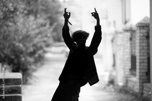 Silhouette of young guy dancing on summer city street