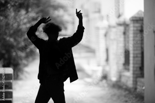 Dark silhouette of young dancer performing on summer street