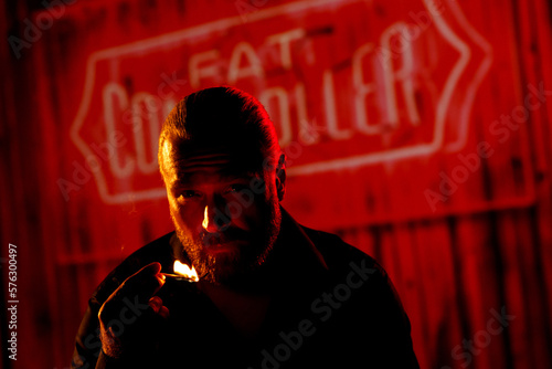 Man with lit match at night against neon sign