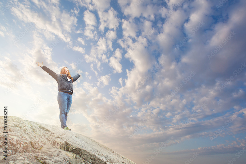 Woman standing and raising hands on a mountain Woman standing and raising hands on a mountain