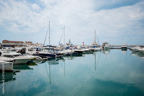 Yacht parking in harbor. Beautiful Yachts in blue sky background. Sailing harbor, many beautiful moored sailing yachts in the seaport, summer vacation, luxury lifestyle and wealth concept.