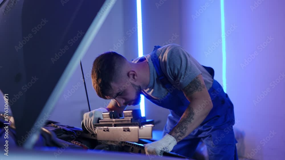 Young concentrated man using flashlight examining automobile engine in garage. Portrait of handsome confident Caucasian auto mechanic checking vehicle at service station indoors Young concentrated man using flashlight examining automobile engine in garage. Portrait of handsome confident Caucasian auto mechanic checking vehicle at service station indoors