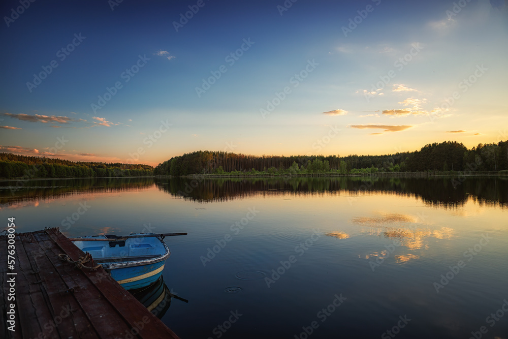 summer evening on the bank of a forest river, a place for fishing on a wooden bridge, and a boat