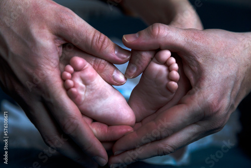 Fototapeta Naklejka Na Ścianę i Meble -  Hands of parents hold the feet of baby