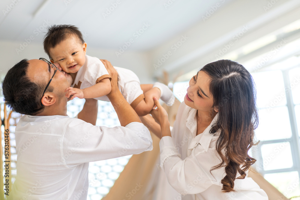 Portrait of enjoy happy love family asian father and mother playing with adorable little asian baby.dad touching with cute son moments good time in a white bedroom.Love of family concept. Portrait of enjoy happy love family asian father and mother playing with adorable little asian baby.dad touching with cute son moments good time in a white bedroom.Love of family concept.