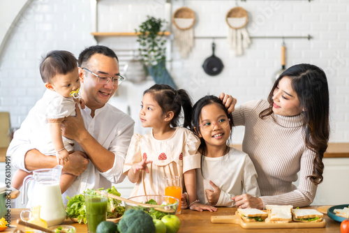 Portrait of enjoy happy love asian family father and mother with little asian girl daughter child having fun help cooking food healthy eat together with fresh vegetable salad and sandwich in kitchen