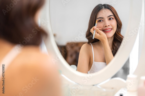 Smiling of young beautiful pretty asian woman clean fresh healthy white skin.asian girl holding make-up brushes and make up on face with cosmetics set at home.facial beauty