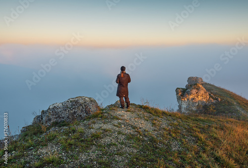 young woman stands on a rock above a river canyon. female tourist enjoys foggy autumn landscape. nature of Ukraine