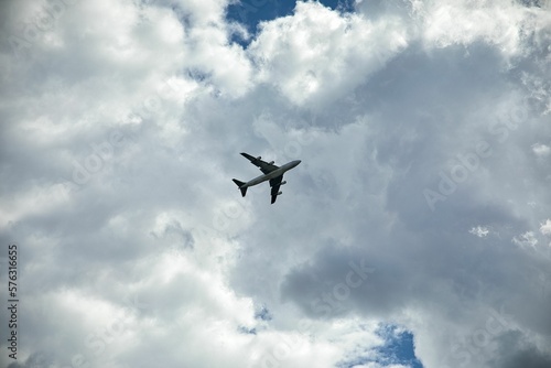 Long-distance shot of a plane directly below him, blue sky with clouds in the background.