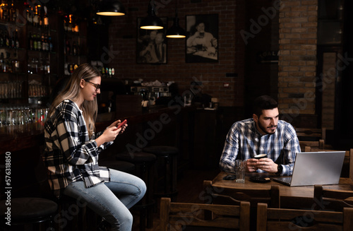 Millennial hipsters husband and wife owners of cafe bar restaurant sitting in the evening after closing talking checking profit, sales calculating order for the next day and resting after a busy day