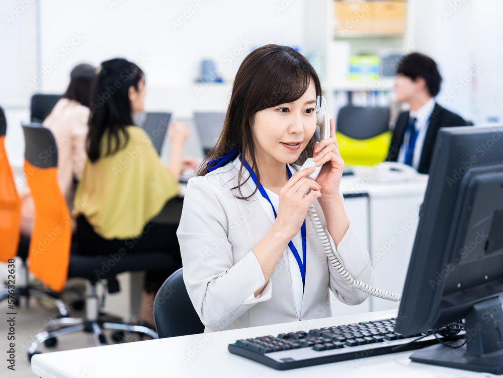 オフィスで固定電話を使う女性 オフィスで固定電話を使う女性