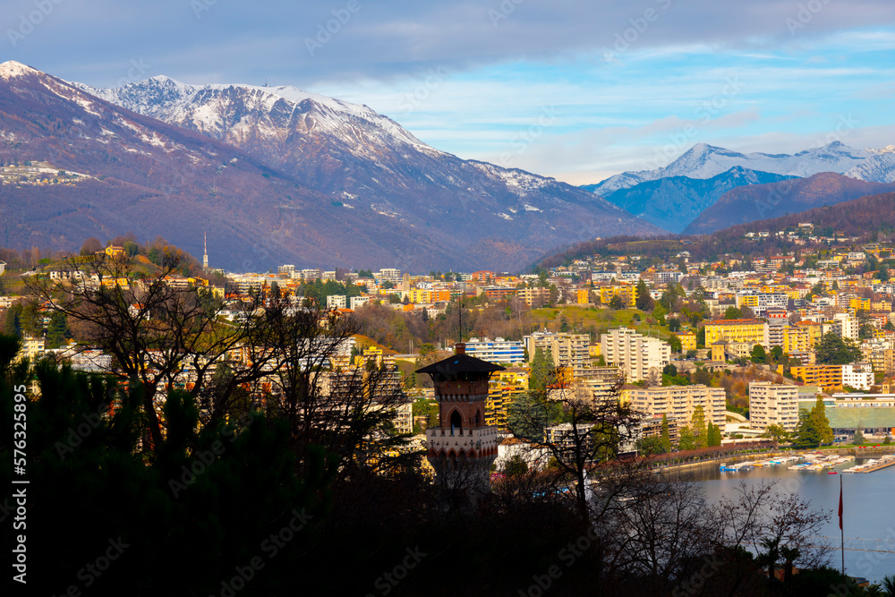 City of Lugano and a Tower with Snow-capped Mountain and Alpine Lake Lugano in a Sunny Day in Ticino, Switzerland.