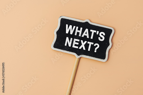 What's Next - text on a small chalkboard on a beige background. Top view. Strategy and vision for work