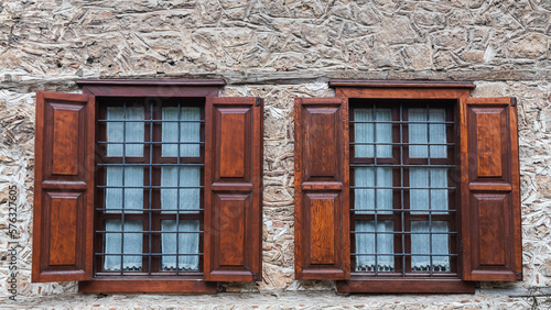 Close-up wall of a stone house with wooden windows and shutters. Old european architecture