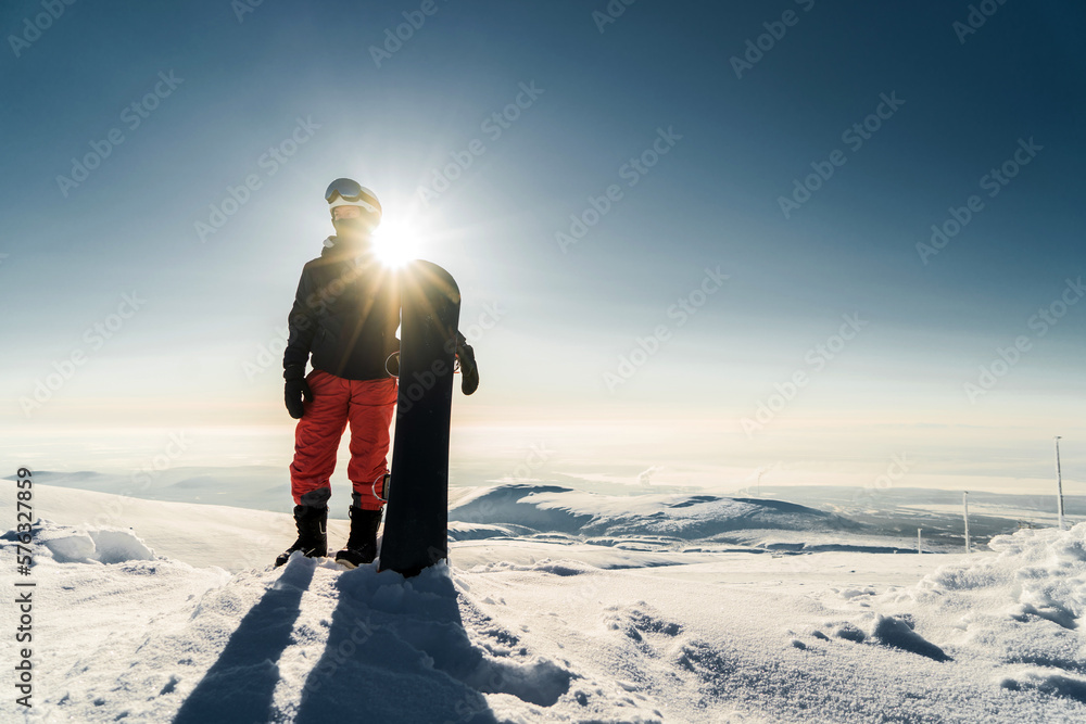 A professional male snowboarder in snowboarding gear at the top of a mountain, a view of the horizon peak. Skiing.