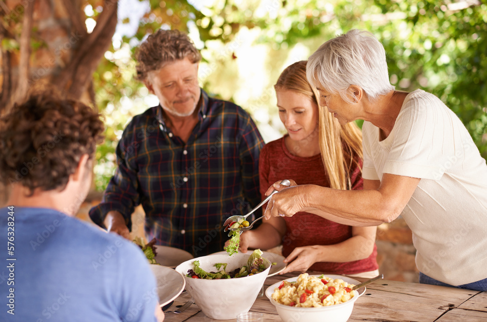 Would you like a little more. A view of a family preparing to eat lunch together outdoors. Would you like a little more. A view of a family preparing to eat lunch together outdoors.