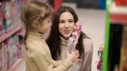 Shopping concept. Mother and daughter are buying dolls in the mall, slow motion photo
