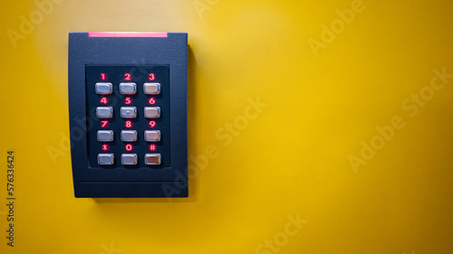 Numeric keypad of smart electronic digital door lock on yellow wall. Password code number for unlock. Security and privacy concept photo