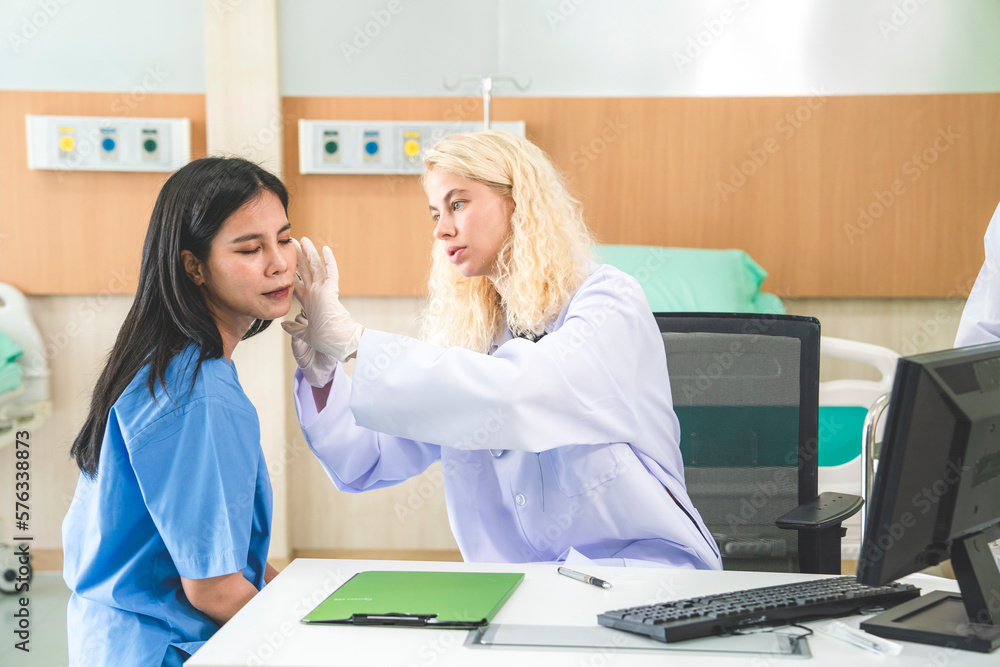 female doctor touches the patient's face to inject fillers to beautify the face and a nurse helps the doctor prepare tools in the hospital.