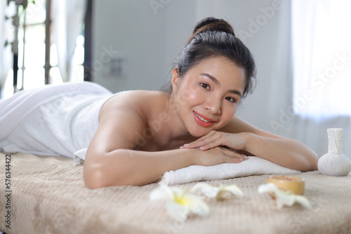 Attractive Asian woman relaxing lying down on bed in Thai massage spa salon.