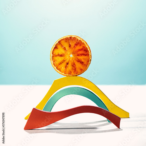 stylized landscape, a sun made with a red orange slice over a  rainbow made with colored wooden shapes