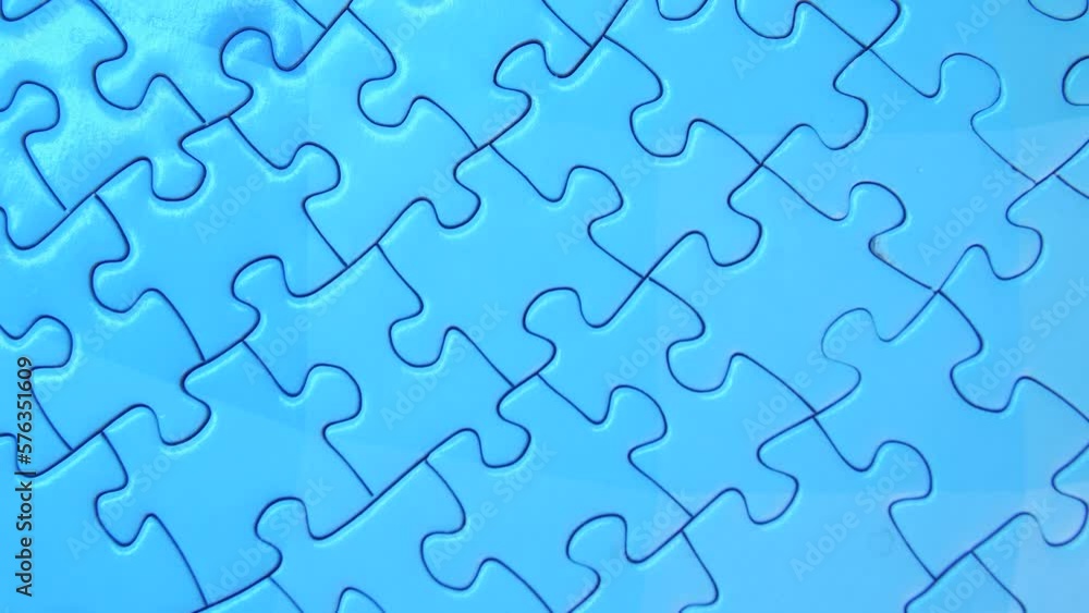 Close-up male hand adding one last piece into jigsaw puzzle picture, teamwork, collaboration, merger of small companies and business ideas into a huge business corporation Close-up male hand adding one last piece into jigsaw puzzle picture, teamwork, collaboration, merger of small companies and business ideas into a huge business corporation