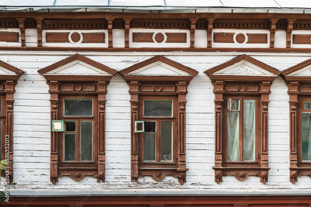 Windows of an old wooden house in carved architraves.
