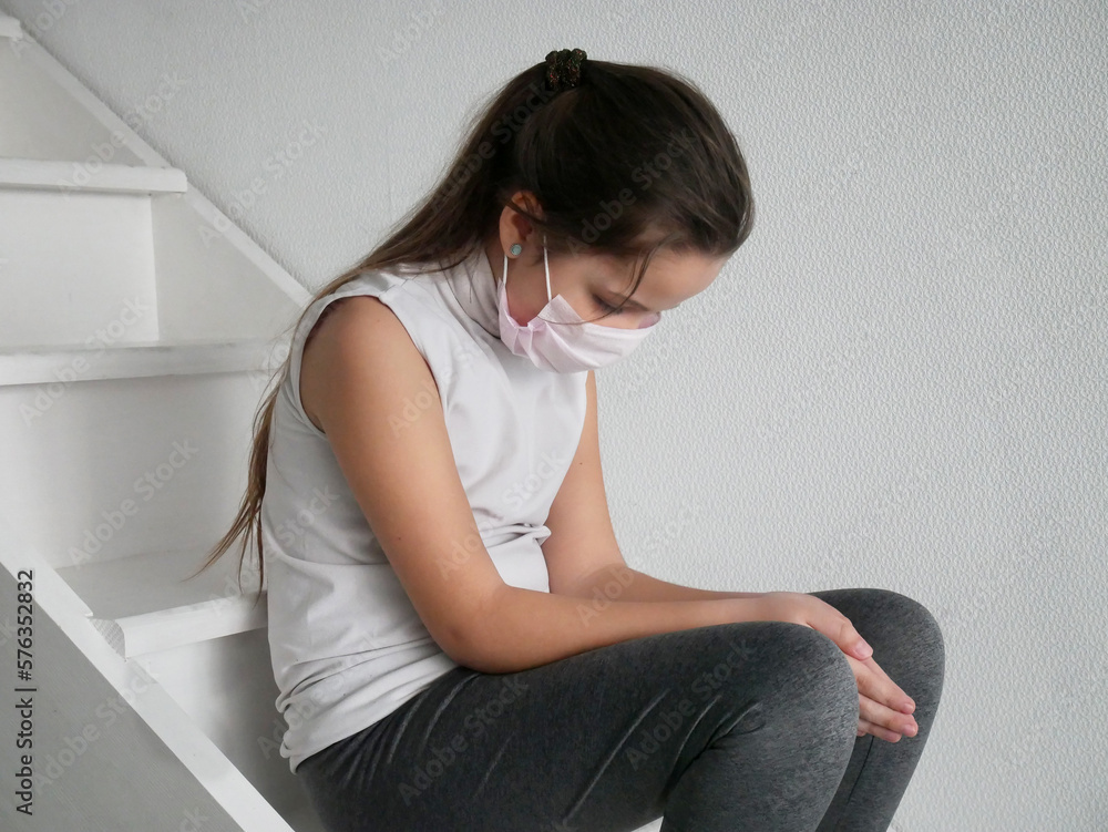 Fototapeta premium Student girl wearing a mask seating on stairs after COVID-19 quarantine and lockdown, sad and tired of not going to school with her friends.