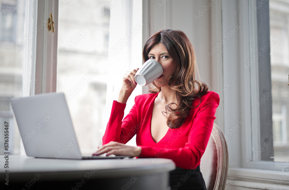 portrait of a young woman drinking tea and working on her computer portrait of a young woman drinking tea and working on her computer