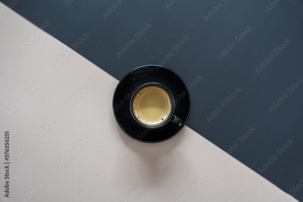Eine Tasse Kaffee auf einem schwarzen und beigen Hintergrund. Kontrast, Gegensatz. Eine Tasse Kaffee auf einem schwarzen und beigen Hintergrund. Kontrast, Gegensatz.